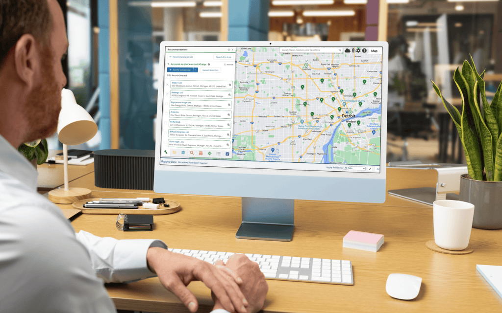 Image of man looking at desktop computer with map of Detroit and recommended places to visit